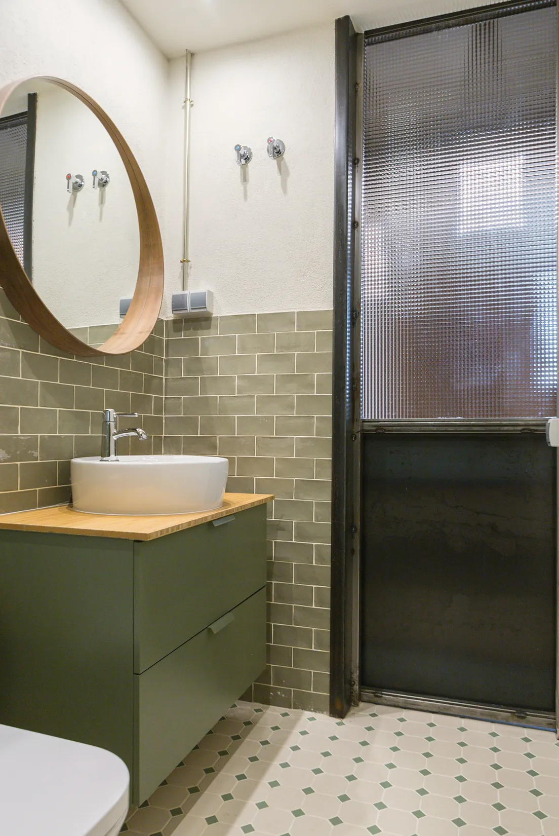 Baño con azulejo oscuro y lavabo sobre mueble verde.. Fotografía 9